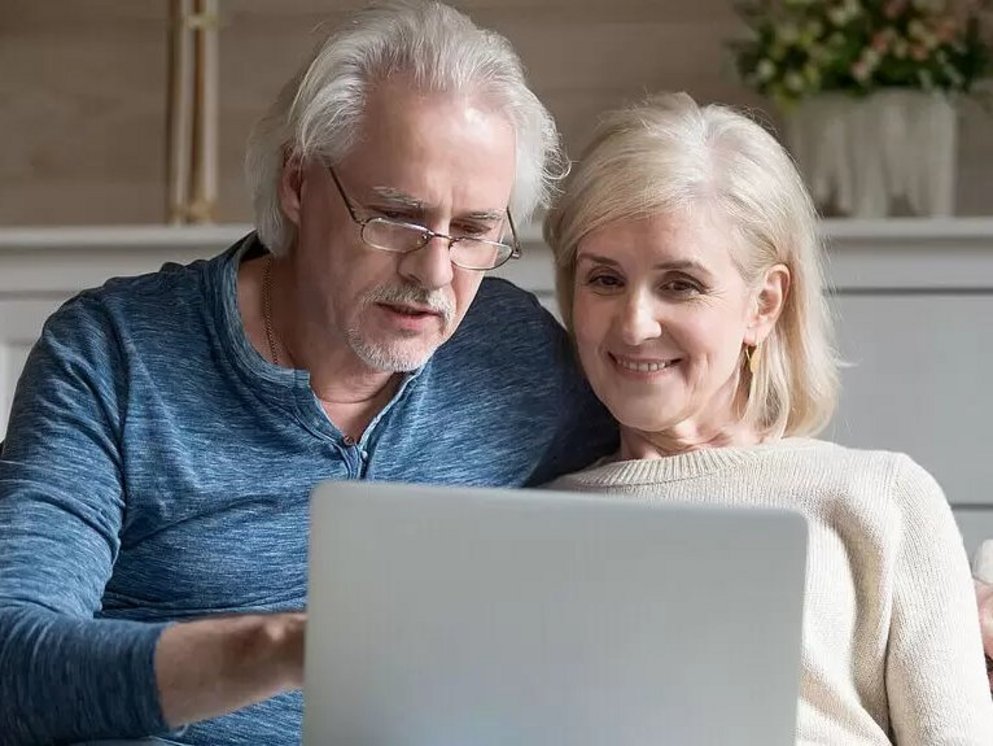 Ein älteres Ehepaar glücklich lächelnd an einem Laptop