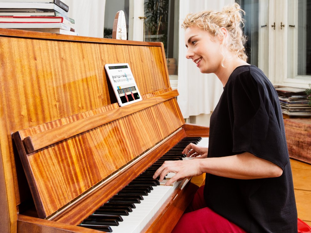 Eine junge Frau die an einem alten Piano mit skoove übt